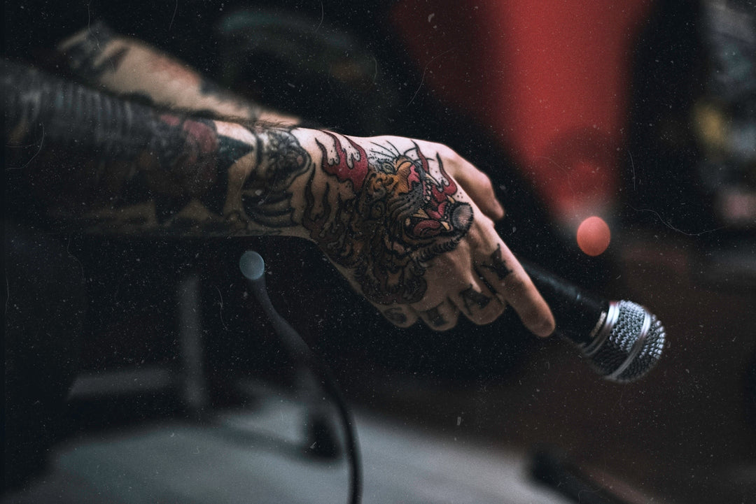 tattooed person holding microphone