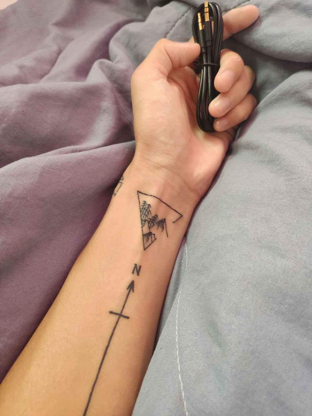 a person with a tattoo on their arm holding a cell phone