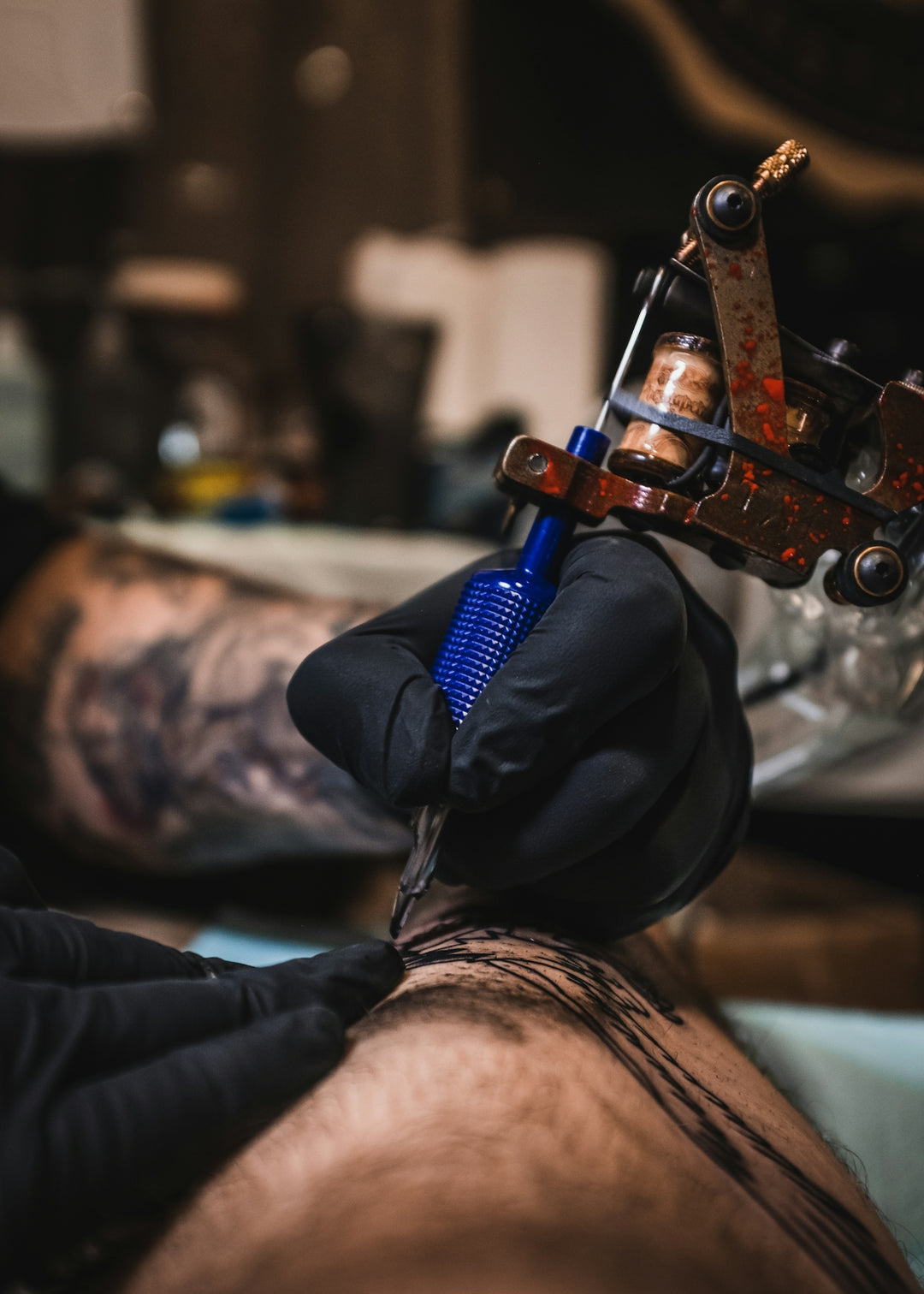 person holding blue and brown tattoo machine