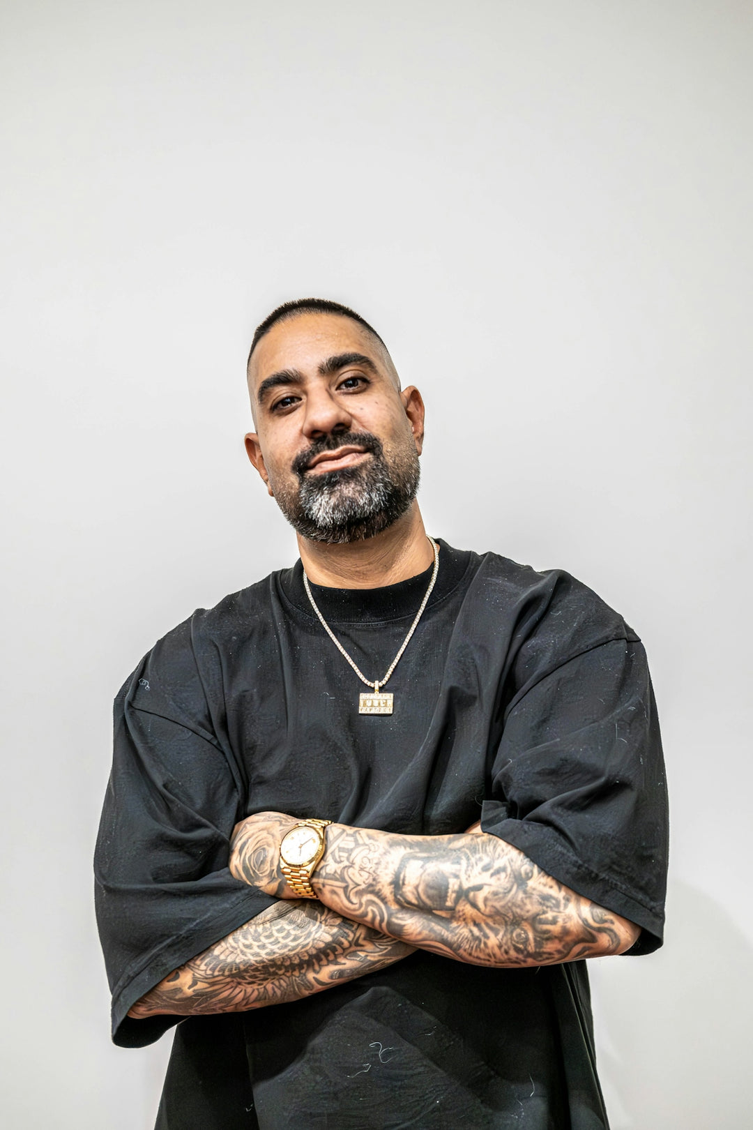A man with tattoos standing with his arms crossed