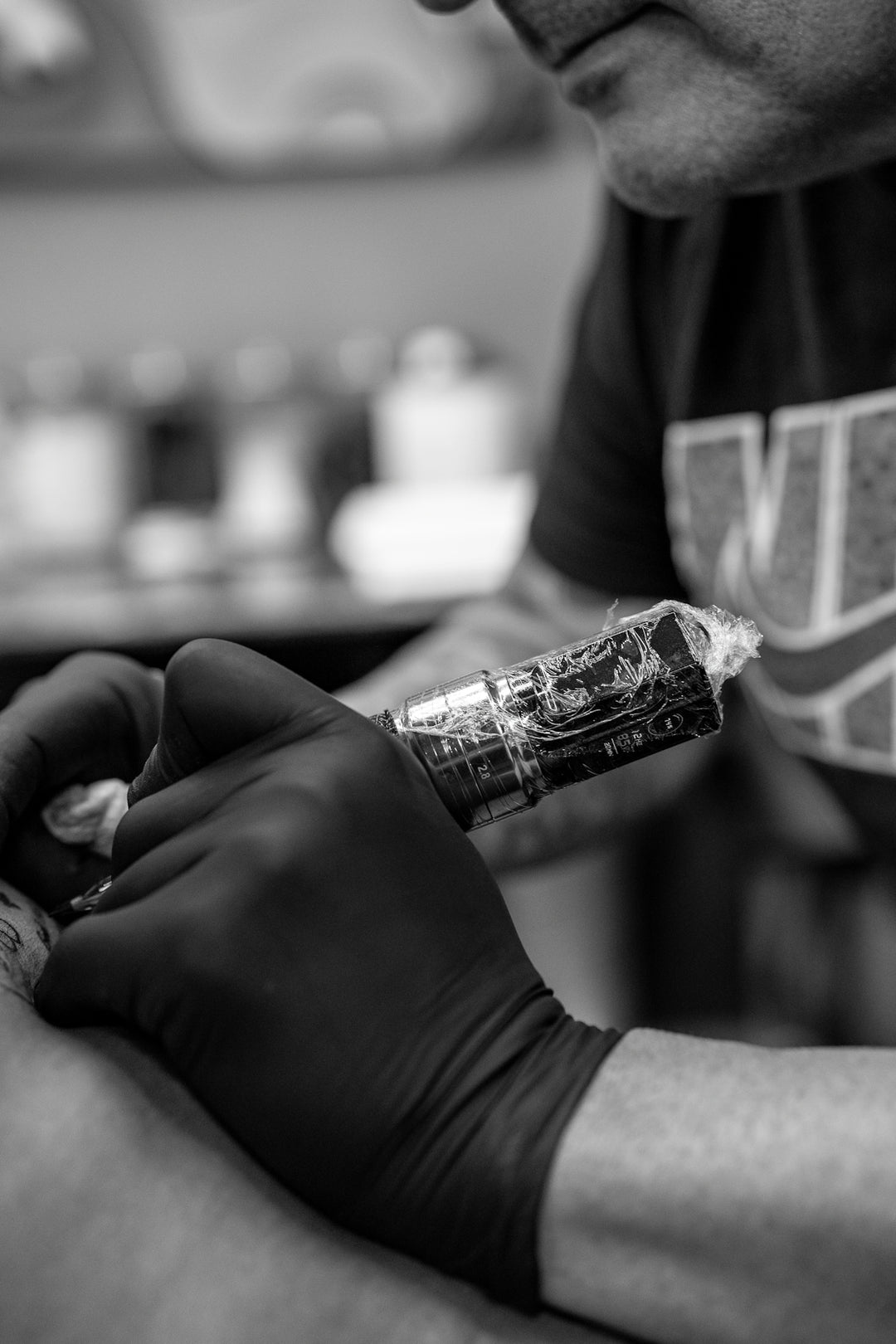 Tattoo artist working on client with black gloves.