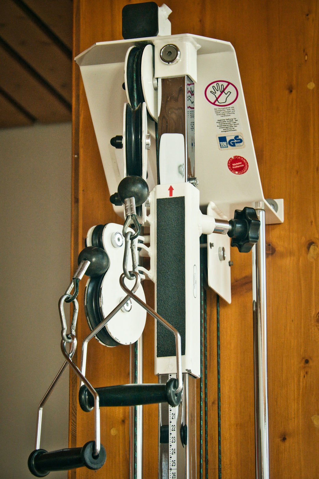 White gym machine with black handles and pulleys