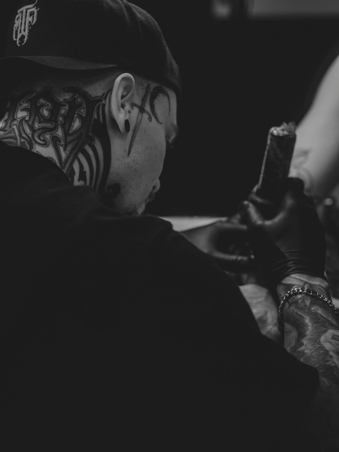 Tattoo artist working on client's arm