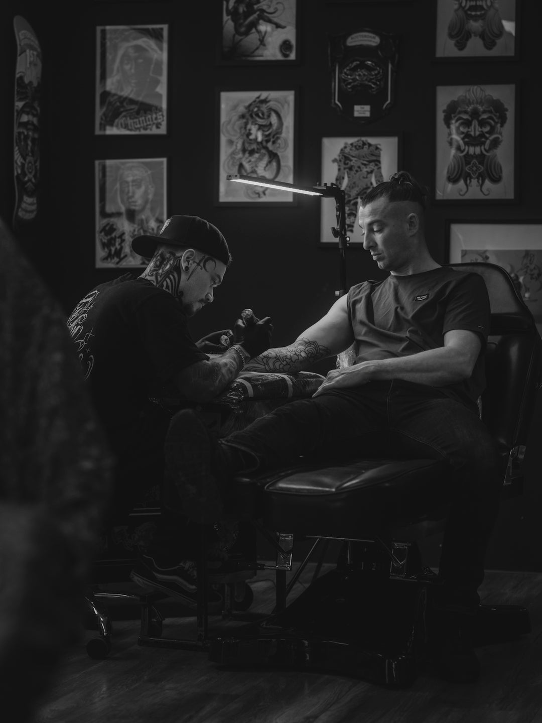 Tattoo artist working on a client's arm in studio.