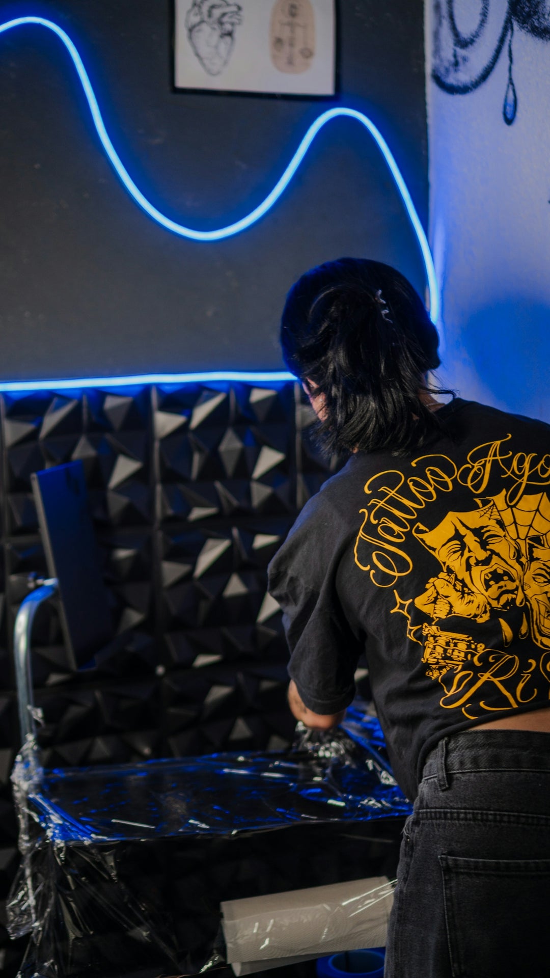 Tattoo artist preparing equipment in a studio with neon light.